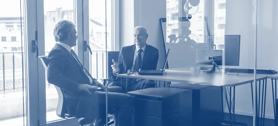 Dois executivos em reunião de trabalho, conversando junto a uma mesa — a diferença entre um financeiro tocado por uma pessoa só e uma operação com equipe dedicada